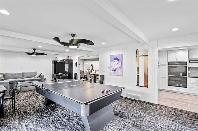 playroom featuring wood walls, ceiling fan, beam ceiling, and dark hardwood / wood-style floors