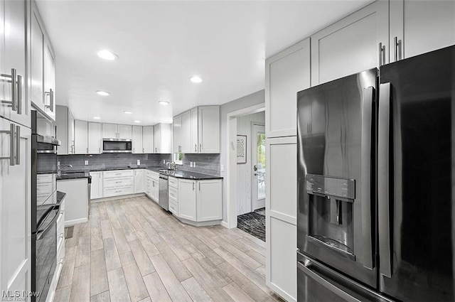 kitchen with white cabinets, backsplash, light hardwood / wood-style floors, and stainless steel appliances