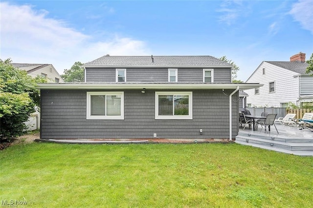 back of property featuring a wooden deck and a lawn