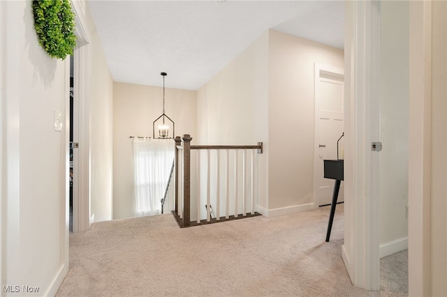 corridor featuring light colored carpet and a notable chandelier