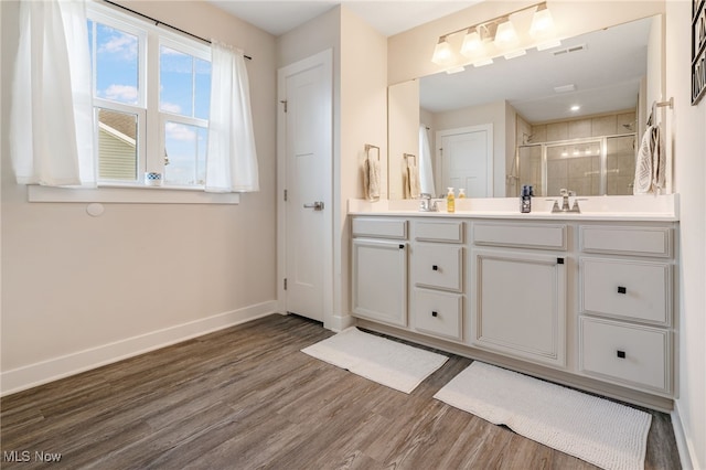 bathroom featuring hardwood / wood-style flooring, vanity, and a shower with door