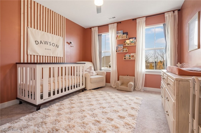 bedroom with ceiling fan, carpet floors, and a crib