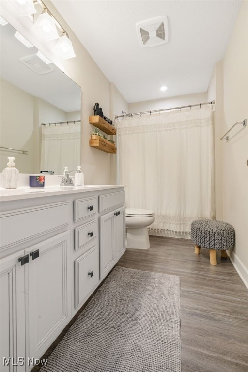 bathroom featuring a shower with curtain, toilet, vanity, and hardwood / wood-style flooring