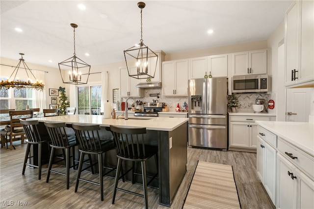 kitchen featuring white cabinetry, a center island with sink, pendant lighting, and appliances with stainless steel finishes