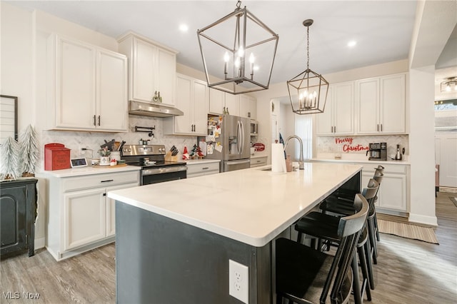 kitchen featuring appliances with stainless steel finishes, a center island with sink, light hardwood / wood-style floors, white cabinetry, and range hood