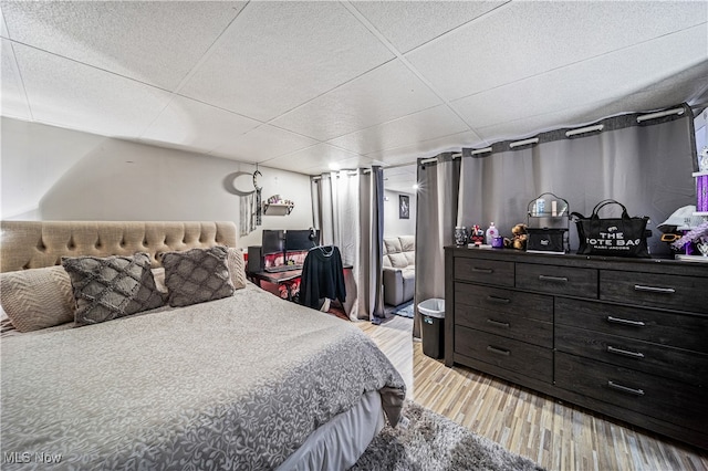 bedroom with a paneled ceiling and light hardwood / wood-style floors