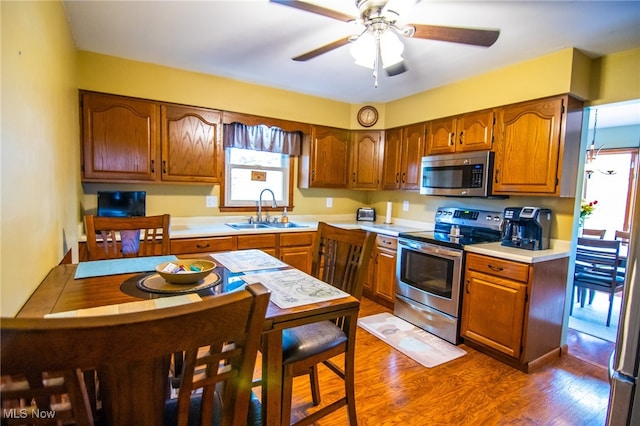 kitchen with appliances with stainless steel finishes, dark hardwood / wood-style flooring, ceiling fan, and sink