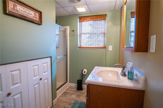 bathroom featuring a paneled ceiling, vanity, and walk in shower