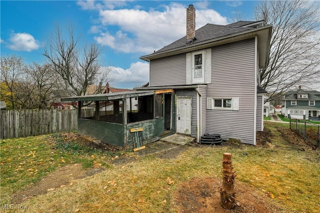 rear view of house with a lawn and a sunroom