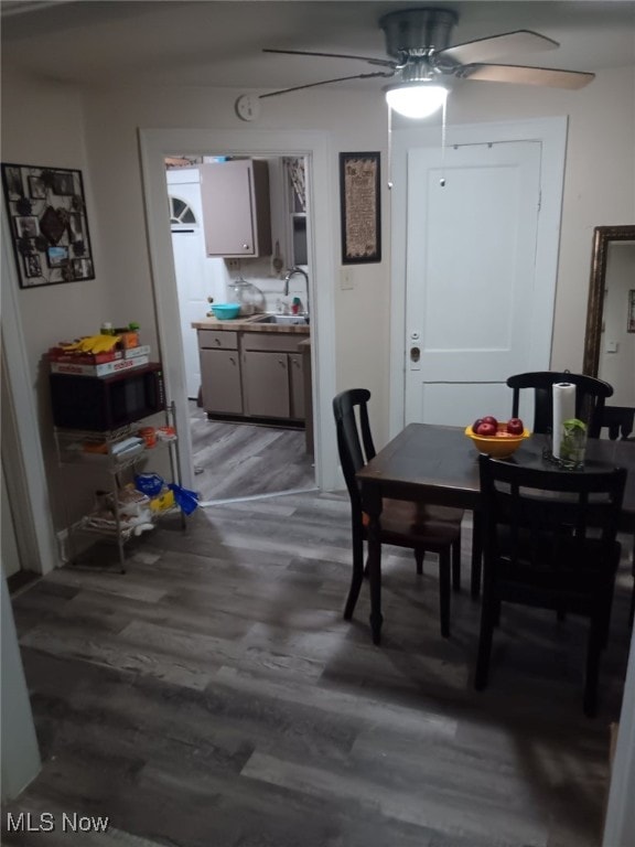 dining area with hardwood / wood-style flooring, ceiling fan, and sink