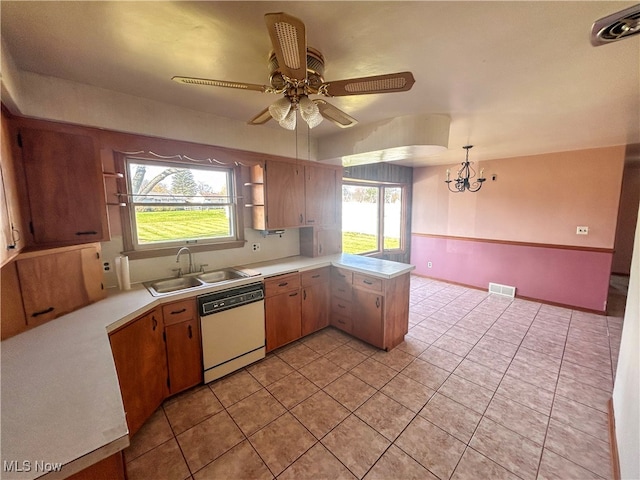 kitchen featuring sink, kitchen peninsula, white dishwasher, decorative light fixtures, and ceiling fan with notable chandelier