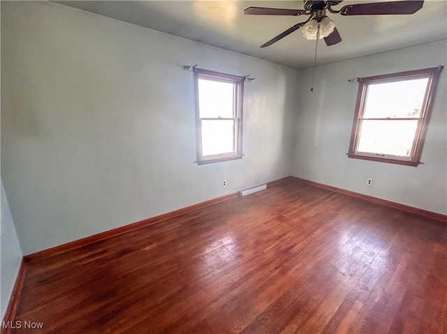 spare room with a baseboard heating unit, ceiling fan, and dark wood-type flooring