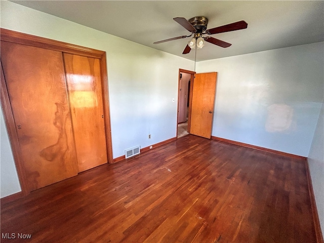 unfurnished bedroom featuring dark hardwood / wood-style floors, ceiling fan, and a closet