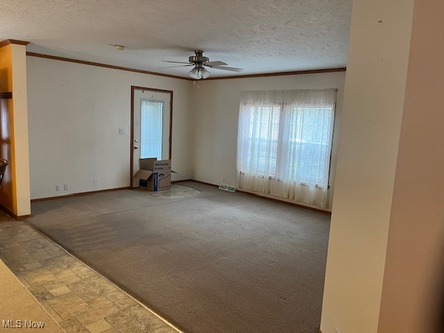 carpeted empty room featuring ceiling fan, crown molding, and a textured ceiling