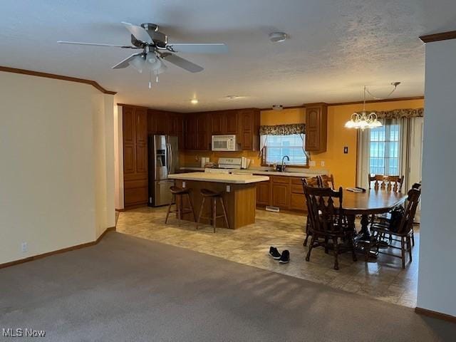 kitchen featuring a center island, sink, white appliances, a breakfast bar, and ceiling fan with notable chandelier