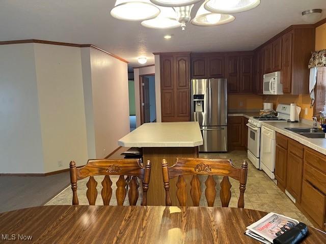 kitchen with crown molding, sink, light tile patterned flooring, and white appliances