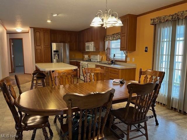 dining space with crown molding, sink, and an inviting chandelier