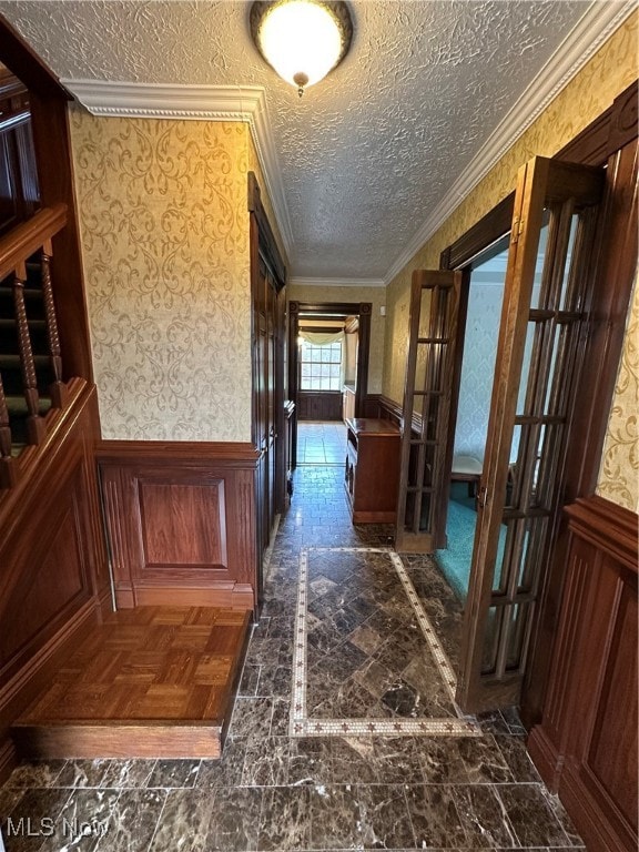 corridor with crown molding and a textured ceiling