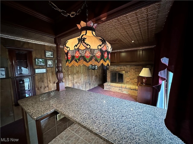 unfurnished dining area with wooden walls, crown molding, and a brick fireplace