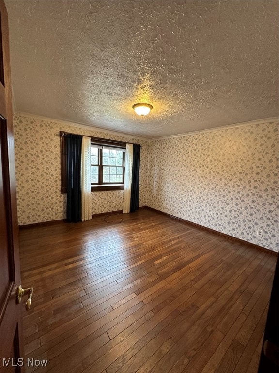 empty room with dark hardwood / wood-style flooring and a textured ceiling