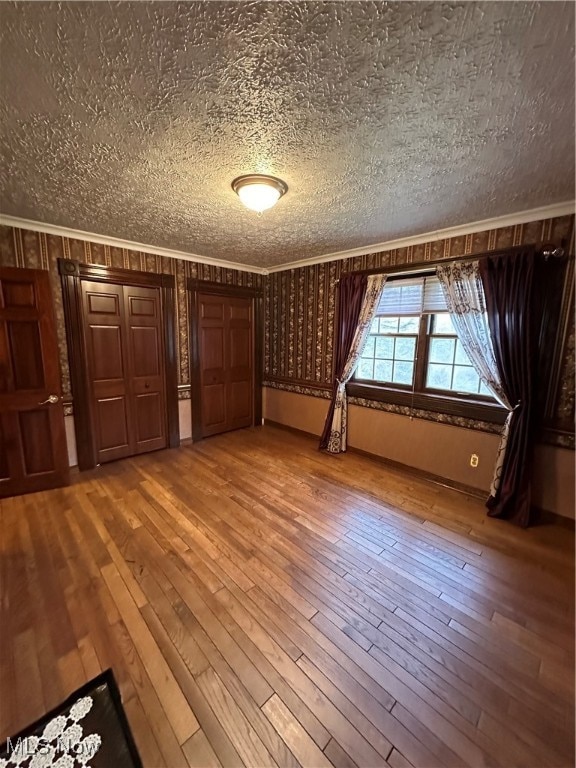 interior space with crown molding, hardwood / wood-style floors, and a textured ceiling