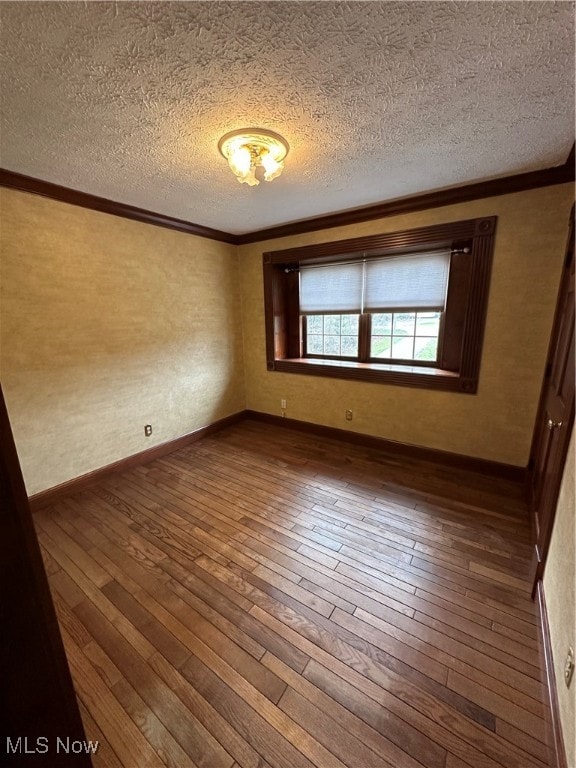 spare room with a textured ceiling, dark hardwood / wood-style flooring, and crown molding