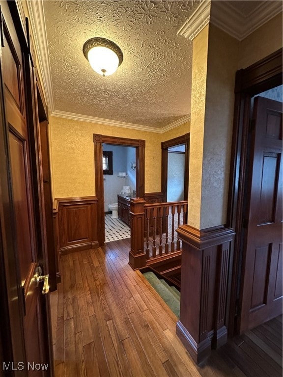 hall featuring hardwood / wood-style floors, a textured ceiling, and ornamental molding