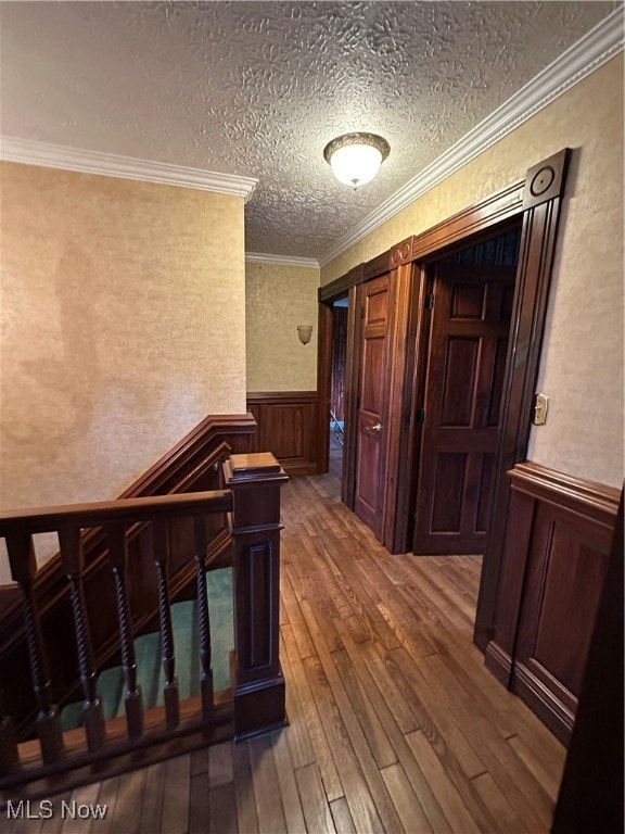 hall with a textured ceiling, hardwood / wood-style flooring, and crown molding