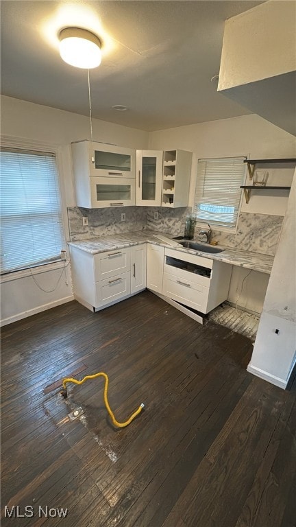 kitchen with tasteful backsplash, white cabinetry, sink, and dark hardwood / wood-style floors