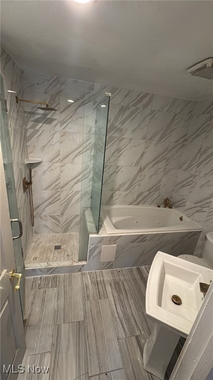 bathroom featuring sink, tile walls, and bath / shower combo with glass door