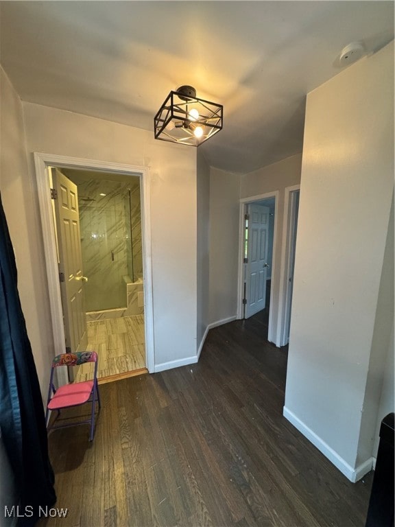 corridor with dark hardwood / wood-style floors and a notable chandelier