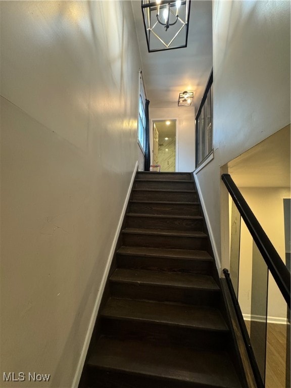 staircase featuring a chandelier and hardwood / wood-style flooring