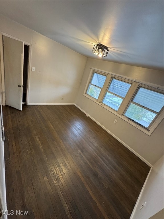 spare room featuring vaulted ceiling and dark wood-type flooring