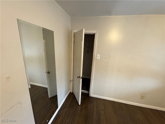 unfurnished bedroom with dark hardwood / wood-style floors and a closet