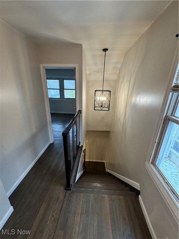 stairway featuring hardwood / wood-style floors, vaulted ceiling, and an inviting chandelier