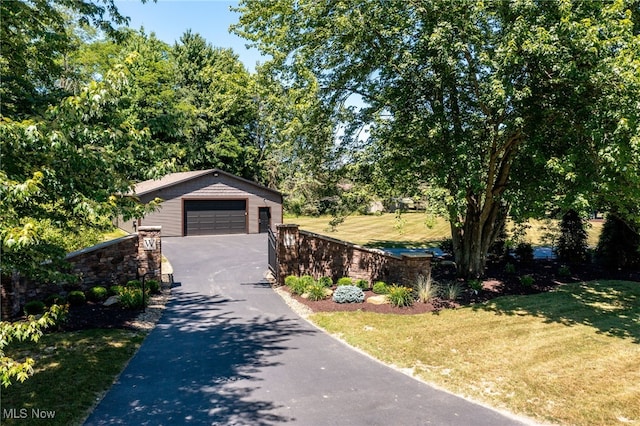 view of front of home with a garage, an outbuilding, and a front lawn