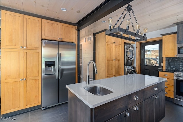 kitchen featuring wood ceiling, stainless steel appliances, sink, a center island with sink, and stacked washer / drying machine