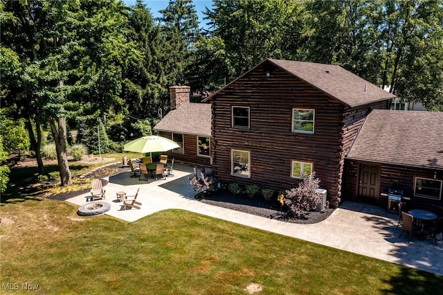 rear view of house with an outdoor fire pit, a patio area, and a lawn