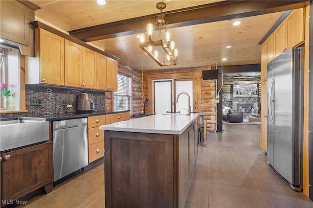 kitchen featuring a center island with sink, hanging light fixtures, a fireplace, stainless steel appliances, and a chandelier