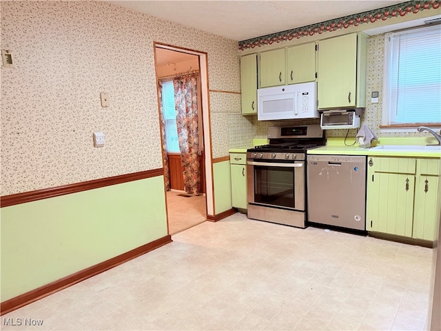 kitchen with appliances with stainless steel finishes, green cabinets, and sink