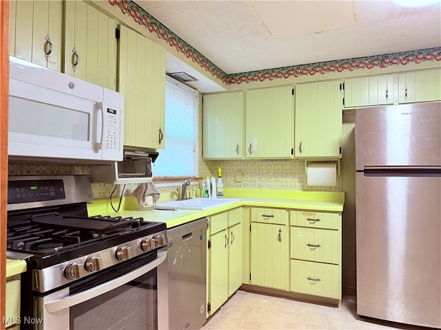 kitchen with a textured ceiling, backsplash, sink, and appliances with stainless steel finishes