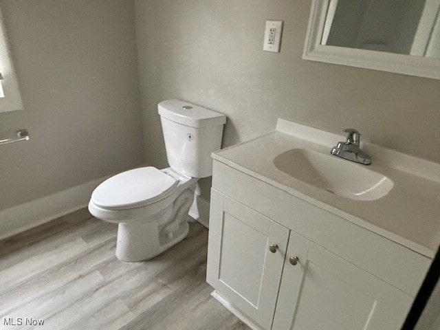 bathroom with hardwood / wood-style floors, vanity, and toilet