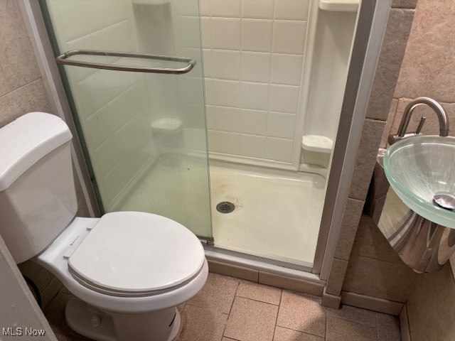 bathroom featuring tile patterned flooring, toilet, a shower with shower door, and sink