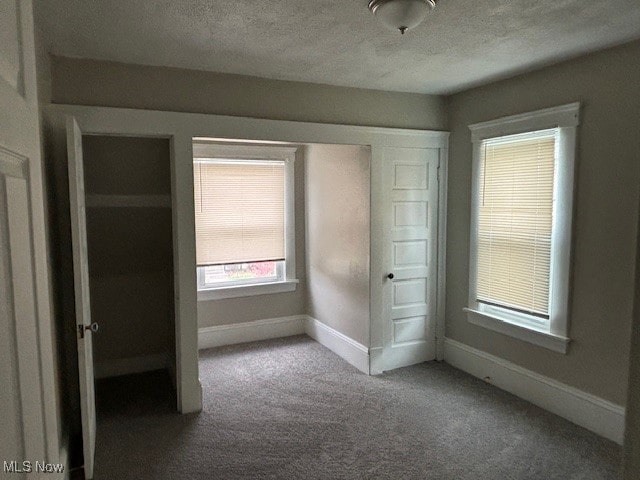 unfurnished bedroom featuring carpet floors, a textured ceiling, and a closet