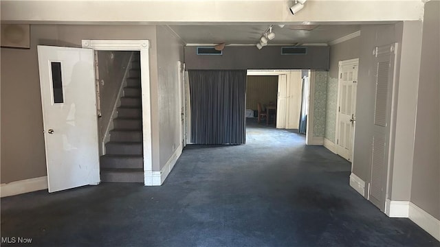 basement featuring crown molding and rail lighting