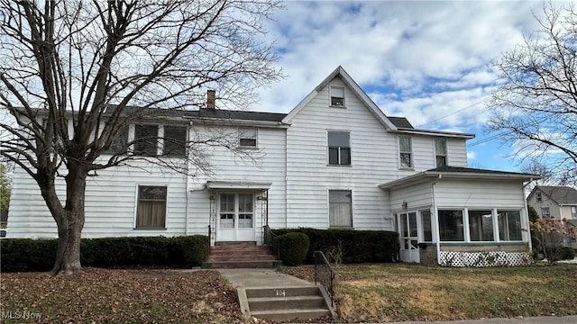 view of front facade featuring a front lawn and a sunroom