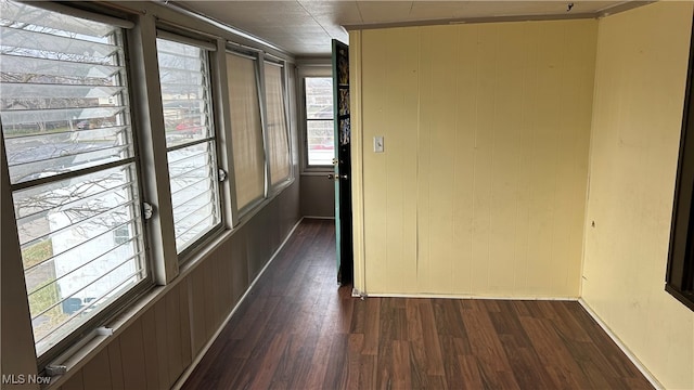 hallway with dark hardwood / wood-style flooring and wood walls