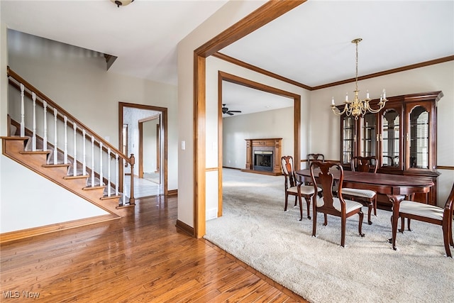 dining room with hardwood / wood-style floors, ceiling fan with notable chandelier, and crown molding