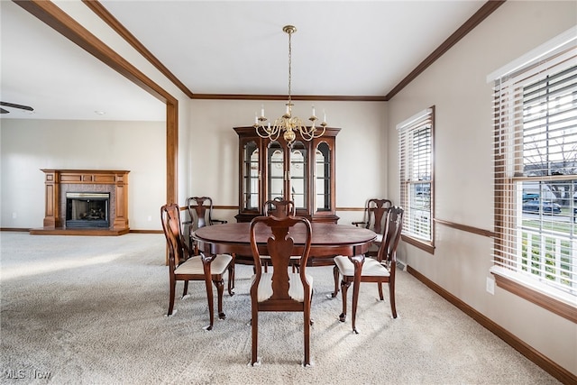 dining room with a chandelier, a wealth of natural light, a high end fireplace, and light carpet