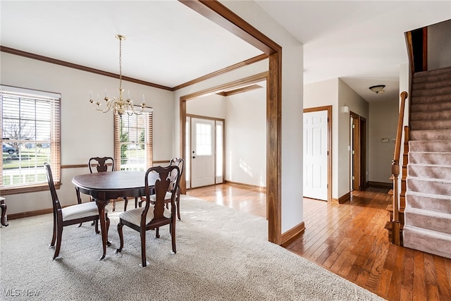 dining space with an inviting chandelier, ornamental molding, and hardwood / wood-style flooring